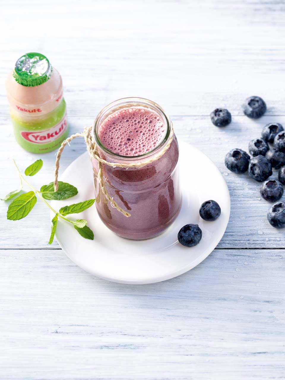 Smoothie met banaan, bosbessen, citroen en flesje Yakult Plus.