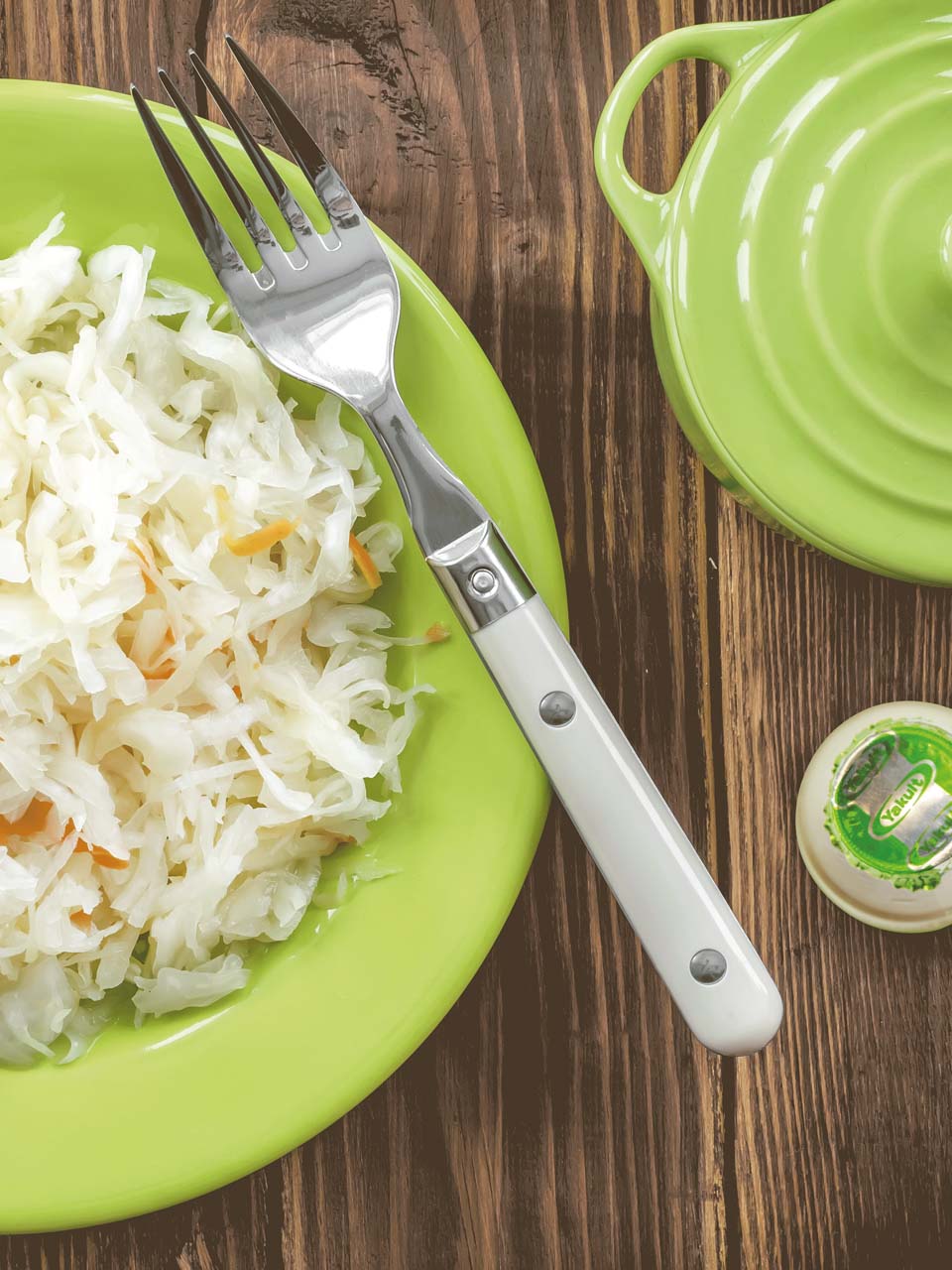 Coleslaw op een bord met fork en flesje Yakult Plus.